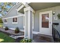 A welcoming front porch with decorative planters, stone landscaping, and a white trimmed front door at 2557 S Dover St # 12, Lakewood, CO 80227
