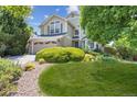 Charming home with lush landscaping, mature trees, and a stone accented front yard at 9823 Salford Ln, Highlands Ranch, CO 80126