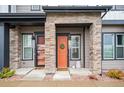 Inviting front entrance features a decorative wreath, stylish orange door, and charming stone accents at 5148 Taft Ct, Wheat Ridge, CO 80033
