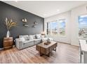 Bright living room featuring a comfortable gray sofa, wood floors, and a large window at 5148 Taft Ct, Wheat Ridge, CO 80033