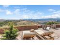 Charming patio with lounge chairs, and a stunning view of distant mountains under a blue sky at 393 Dixon Rd, Boulder, CO 80302