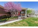 Inviting covered front porch with a red door, decorative wreath, and pretty landscaping at 13668 Plaster Cir, Broomfield, CO 80023