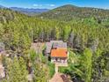 Aerial view of a cozy home nestled amongst towering trees in a beautiful mountain setting at 9092 Gray Ln, Conifer, CO 80433
