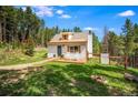 Lovely one-story home features a manicured lawn with a wood fence and rock fire pit at 9092 Gray Ln, Conifer, CO 80433