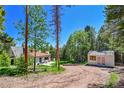 Exterior view of a charming home with a copper roof and separate building, surrounded by trees and a dirt driveway at 9092 Gray Ln, Conifer, CO 80433