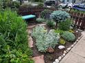 Landscaped front yard with a variety of plants, stone pavers, and a cozy bench for enjoying the outdoor space at 34 W Maple Ave, Denver, CO 80223