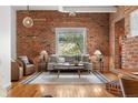 Inviting living room boasts exposed brick wall, large window, modern furniture, and hardwood floors, creating a cozy atmosphere at 624 E 18Th Ave # 3, Denver, CO 80203