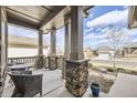 Inviting covered front porch features stone pillars, wrought iron railings, and a comfortable seating area at 15831 Lavender Pl, Broomfield, CO 80023