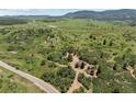 Lush landscape features a rural home, surrounded by greenery with a winding road leading to the tranquil property at 8821 S Perry Park Rd, Larkspur, CO 80118