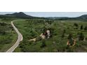 Picturesque landscape of rolling hills and green pastures, dotted with homes and a winding road in the distance at 8821 S Perry Park Rd, Larkspur, CO 80118