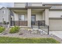 Covered front porch with stone accents, black metal railings, and manicured landscaping at 12749 Horton Ct, Parker, CO 80134