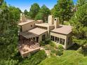 An aerial view of a stucco home with a pergola patio, lush landscaping, and a serene setting at 2107 Ridge Plaza Dr, Castle Rock, CO 80108