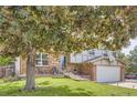 Inviting front yard with a mature tree shading the house, a well-maintained lawn, and a cozy seating area on the porch at 16602 E Gunnison Pl, Aurora, CO 80017