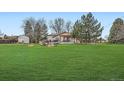 Expansive backyard featuring a well-maintained lawn and a charming house with a spacious deck at 5855 Rustic Knolls Dr, Boulder, CO 80301
