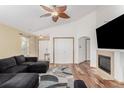 Bright living room featuring a dark gray sofa, wood floors, fireplace, and decorative ceiling fan at 16257 E 105Th Cir, Commerce City, CO 80022