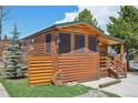 Attractive log cabin featuring a covered porch and manicured lawn, set against a blue sky at 85 Revett Dr # 40, Breckenridge, CO 80424