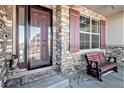 Front entrance with stonework, a wooden bench, and a burgundy door at 11898 Discovery Cir, Parker, CO 80138