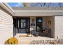 Cozy front porch featuring a black door, stylish bench, autumn decor, and attractive stone landscaping at 7107 E Costilla Dr, Centennial, CO 80112