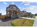 Charming two-story home with a cozy front porch, stone accents, and a beautifully landscaped front yard at 13221 E 110Th Pl, Commerce City, CO 80022