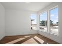 Bright bedroom with hardwood floors and three large windows offering natural light and suburban views at 5584 Moosehead Cir, Longmont, CO 80504