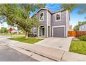 Home exterior features a two-story design with gray siding, green door, an attached garage, and lawn with a mature tree at 5320 E 100Th Dr, Thornton, CO 80229