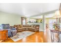Living room area has warm wood floors and multiple sofas with an opening to the dining area at 5320 E 100Th Dr, Thornton, CO 80229