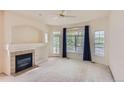 Bright living room with fireplace, large windows with backyard view and a ceiling fan at 29 Woodland Cir, Highlands Ranch, CO 80126