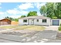 Beautifully renovated white exterior with well-manicured lawn and modern blue accents on doors and trim at 6500 W 32Nd Ave, Wheat Ridge, CO 80033