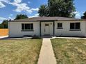 Charming home featuring a covered front porch, white paint, and a well-manicured lawn at 6500 W 32Nd Ave, Wheat Ridge, CO 80033