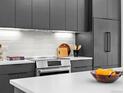 Close-up of a modern kitchen with sleek black cabinets, stainless steel appliances, and a white tile backsplash at 1601 Park Ave # 212, Denver, CO 80218
