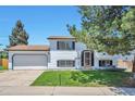 Split level home featuring a two car garage, front lawn and mature trees at 9135 W Maplewood Ave, Littleton, CO 80123
