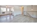 Open living room with light gray laminate flooring and staircase with decorative metal railing at 9135 W Maplewood Ave, Littleton, CO 80123