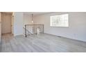 Bright living room featuring light gray laminate flooring and staircase with metal railing at 9135 W Maplewood Ave, Littleton, CO 80123