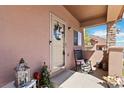 Close-up of front door with rocking chair, decorative lantern, and covered porch area at 15501 E 112Th Ave # 20C, Commerce City, CO 80022