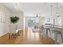 Open-concept living and dining area with hardwood floors, a modern ceiling fan, and a kitchen counter with stools at 13456 Via Varra # 211, Broomfield, CO 80020