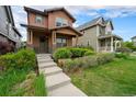 Inviting two-story home featuring a covered front porch, a well-maintained lawn, and mature landscaping at 5434 N Xenia St, Denver, CO 80238