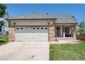 Charming home featuring a two-car garage with stylish brick accents, a covered porch and a well-kept lawn at 5033 Goshawk Ct, Brighton, CO 80601