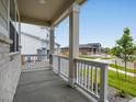 Inviting covered porch with white columns, overlooking a landscaped front yard and quiet street at 17424 E 90Th Pl, Commerce City, CO 80022