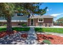Charming house features brick and siding, mature tree, landscaping, and a cozy front yard at 16225 W 74Th Dr, Arvada, CO 80007