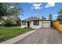 View of exterior showing the well kept lawn and a one car garage with a gravel driveway at 11842 W 14Th Ave, Lakewood, CO 80401