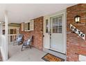 Inviting front porch features brick accents, cozy seating, and a charming welcome mat, enhancing curb appeal at 6836 E Briarwood Dr, Centennial, CO 80112