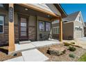 Inviting covered porch with stylish seating and stone landscape accent at 16277 Talons Bluff Ln, Monument, CO 80132
