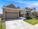 Inviting single Gathering home showcasing stone accents, a spacious driveway, and manicured lawn at 16448 E 111Th Pl, Commerce City, CO 80022
