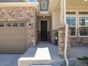 Welcoming front porch featuring stone pillars, neutral siding, and an elegant black front door at 16448 E 111Th Pl, Commerce City, CO 80022