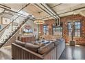 Stylish living room featuring exposed brick, industrial-style ceiling, and modern staircase to the upper level at 1863 Wazee St # 6B, Denver, CO 80202