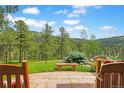 Picturesque backyard features a stone bench, lush trees, and views, perfect for relaxation and enjoying the natural surroundings at 2398 Bitterroot Ln, Golden, CO 80401