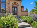 Inviting front entrance with a gated arched doorway, stone accents, and manicured landscaping at 2256 S Isabell Ct, Lakewood, CO 80228