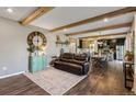 Open-concept living room and kitchen featuring wood beam ceilings and hardwood floors, great for entertaining at 42891 Hawktree Cir, Elizabeth, CO 80107