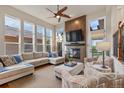 Open concept living room featuring a fireplace, large windows, and cozy seating area with natural light at 6874 Raspberry Run, Littleton, CO 80125