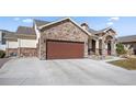 View of home featuring stone accents and a large driveway leading to a 2 car garage at 156 Chapel Hill Cir, Brighton, CO 80601